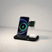Blessing Sells 3-in-1 wireless charging stand in black, charging a smartphone, smartwatch, and earphones. Minimalist design.