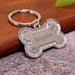 Blessing Sells silver bone-shaped pet ID tag with glitter border and engraved name 'Angela', paw print, and bone icon.