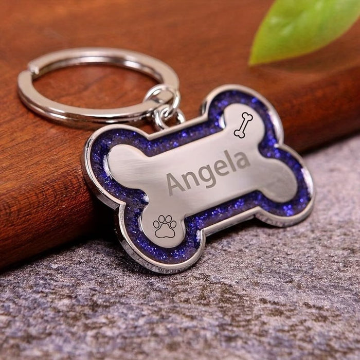 Blessing Sells personalized silver bone-shaped pet ID tag with glittery purple border and paw print engraving.